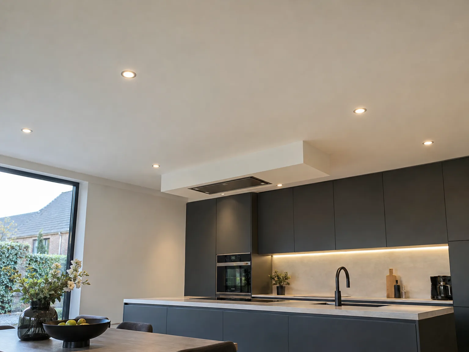 Moderne geplaatste keuken met zwarte fronten, wit werkblad, LED-verlichting en ingebouwde apparatuur
